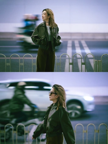 一位穿着外套的女人走在靠近汽车的一条街上