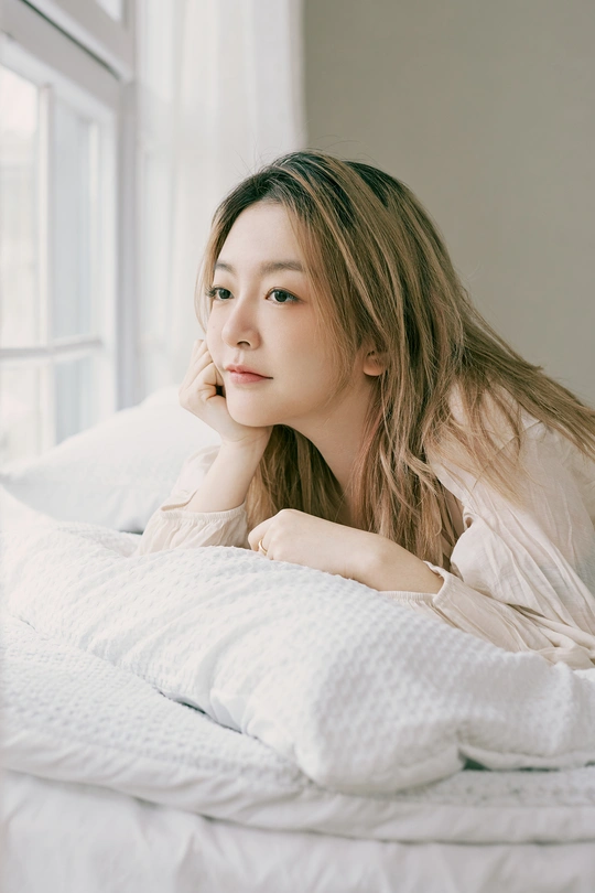 一个美丽的年轻女子躺在床上 下面铺着一条白色的毛毯。