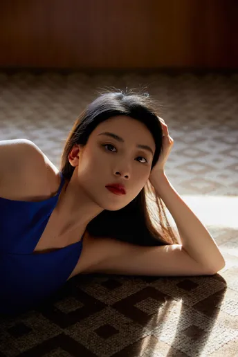 一个穿着蓝色连衣裙的年轻女子躺在光线昏暗的房间里