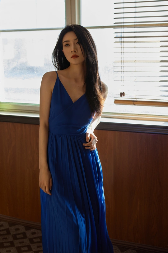 一个人穿着蓝色连衣裙站在一个靠近窗户的房间里