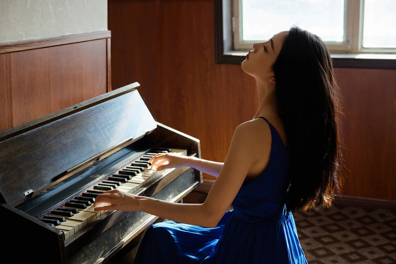 一位穿着蓝色连衣裙的年轻女子正在弹钢琴