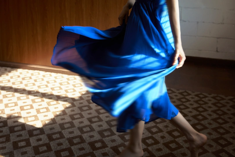 一个穿着蓝色连衣裙的女人在昏暗的光线下走下走廊
