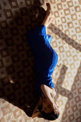 一个穿蓝色衬衫的年轻女子躺在地板上 另一个人也躺在地板上。