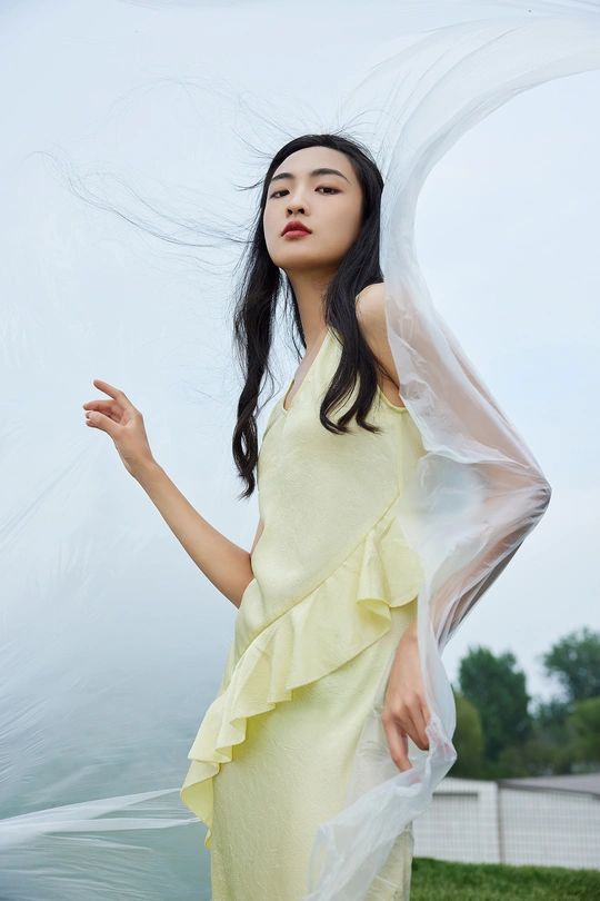 一位穿着黄色连衣裙的美女站在外面