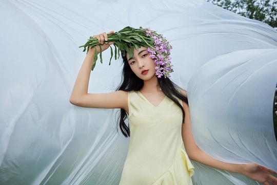 一位穿着黄色连衣裙 手持白色雨伞 头戴绿植的美丽年轻女子