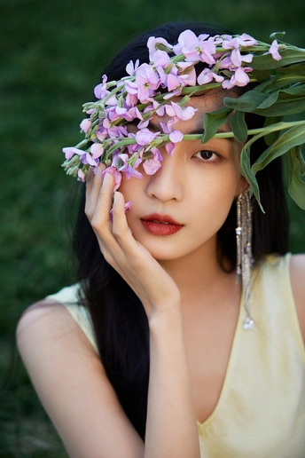 一位头戴紫花环的年轻女子正在为肖像画做姿势。