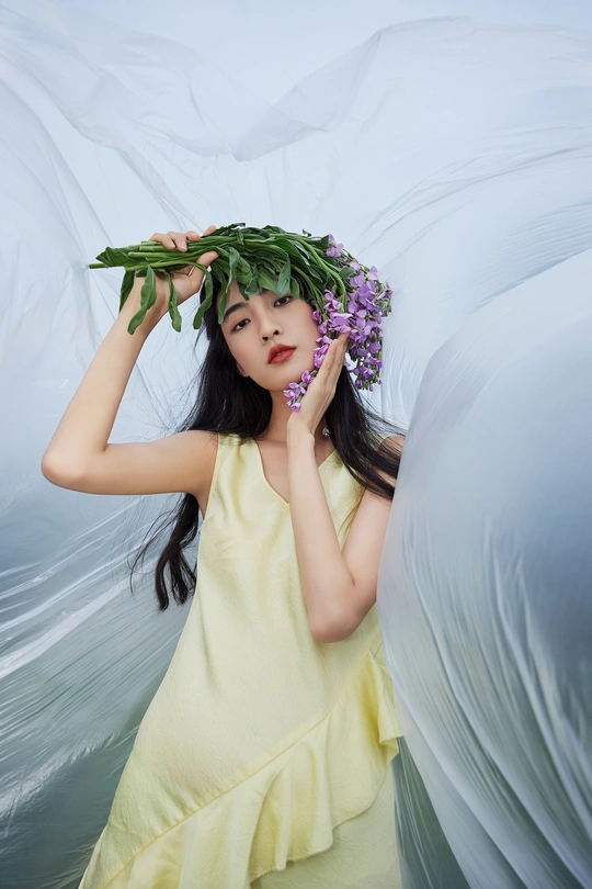 一位穿着黄色连衣裙的美女 头戴一束紫花绿叶的鲜花环。