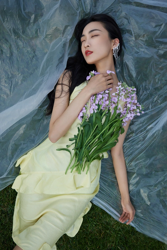 一位穿着黄色连衣裙 手持紫色花束的美丽年轻女子