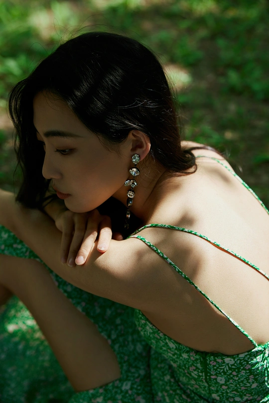 一个穿着绿裙子的美丽年轻女子坐在草地上