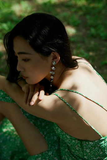一个穿着绿裙子的美丽年轻女子坐在草地上