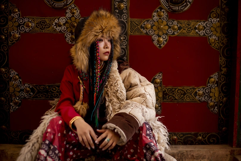一位穿着红色皮草大衣坐在楼梯上的女性 身着传统服装