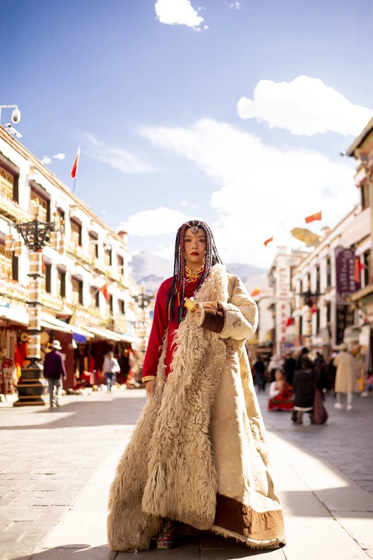 一位穿着皮草和外套的传统服装的年轻女子走在街上。