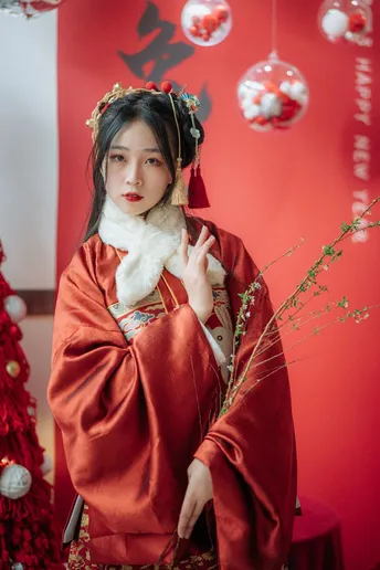 一位穿着传统服装的女孩在圣诞树下摆姿势