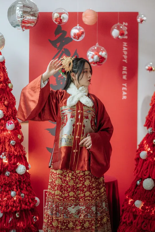 一位穿着传统服装的女性在圣诞树下摆姿势