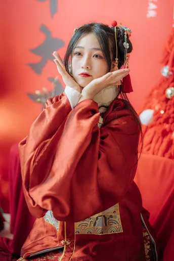 一位穿着红色和服的年轻女子在圣诞树下穿着传统服装摆姿势