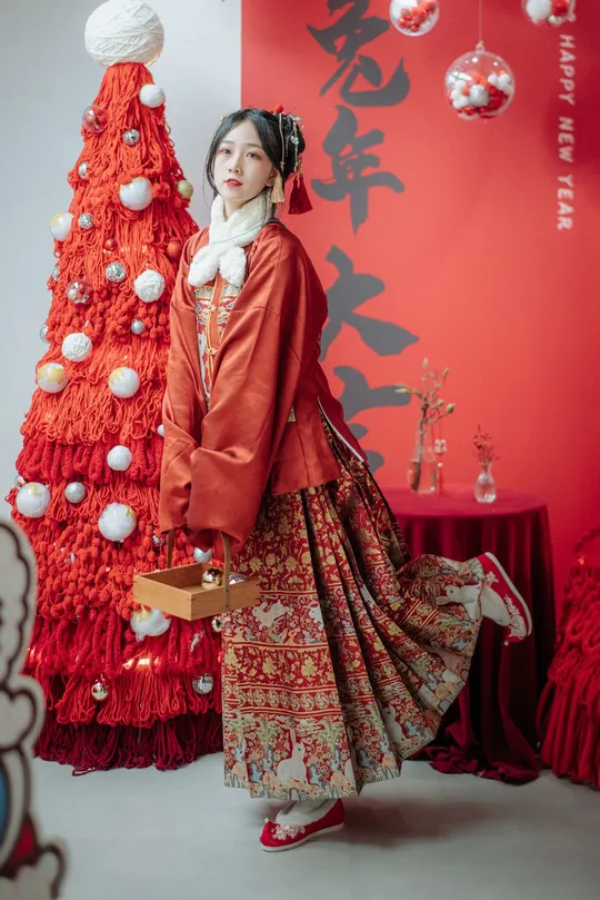 一位穿着传统服装的女性站在圣诞树前