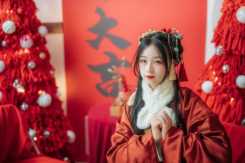 一位穿着圣诞节服装的年轻女子站在圣诞树前