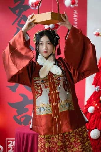 一位身着传统服装的年轻女子头顶上放着一个盒子。