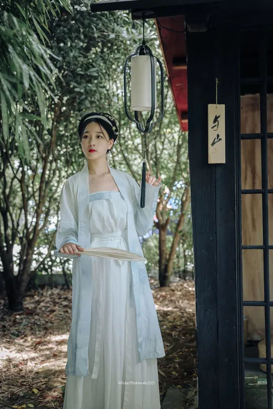 一位穿着传统白色连衣裙的女孩站在门前