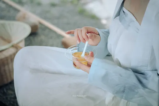 一位穿着白色连衣裙的女性拿着一杯水