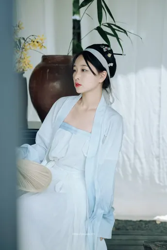 一位穿着白色长袍的女子站在一个花瓶前面