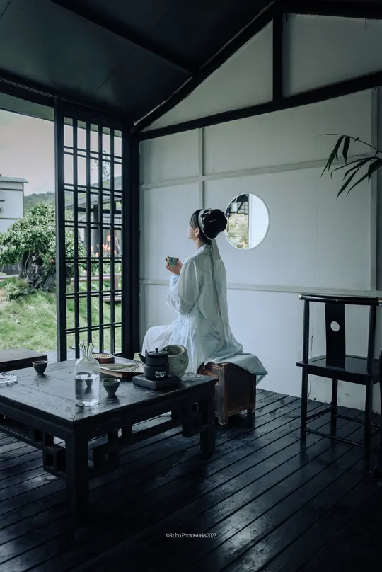 一个坐在带大窗户房间的木制桌子上的白人妇女