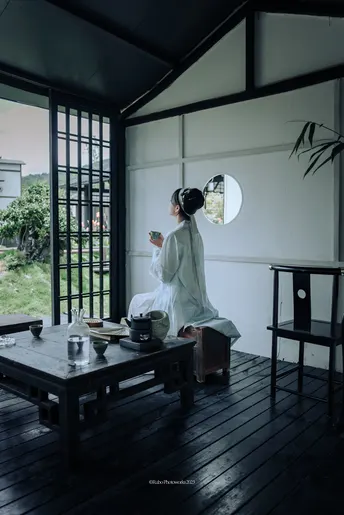 一个坐在带大窗户房间的木制桌子上的白人妇女