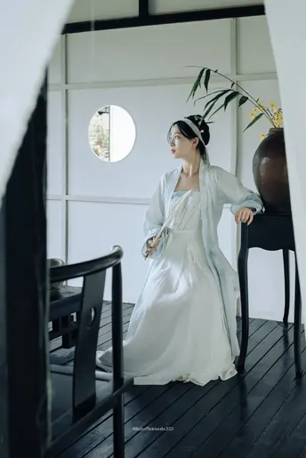 一位穿着白色连衣裙站在椅子旁边的女士