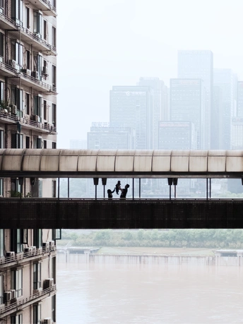 一座横跨在大片水域上的桥 桥上有人行走 背景是城市中的建筑。