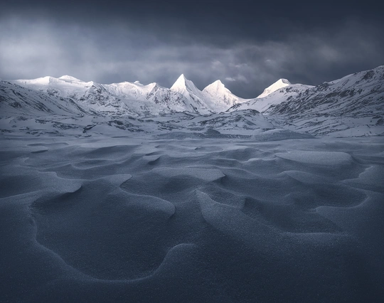 一片白雪皑皑的山脉 天空中乌云密布。
