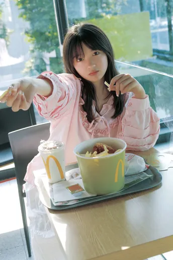 一个穿粉色衣服的年轻女子坐在桌子旁吃一碗麦片。