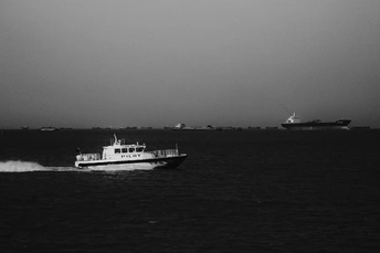 一艘小船在一大片水域中行驶的黑白照片