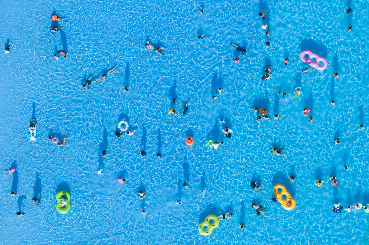 许多人正在海滩上蓝色的水中游泳。