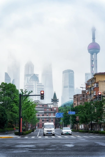 一辆白色货车沿着一个交通灯附近的街道行驶 背景是建筑物 一辆汽车在公路上行驶。