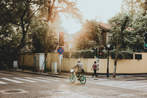 一个人骑着绿色自行车穿过十字路口的人行横道 孩子正在过街