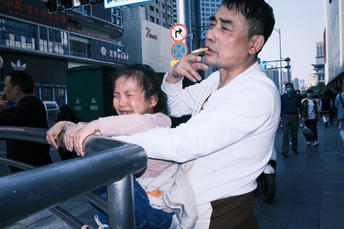 一个含着孩子的男人站在繁忙的街道上