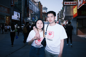 一位年轻男子和一位年轻女子在繁忙的城市街道人行道上拍照 此时 一个男孩和一个女孩正在街上走。
