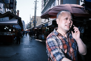 一个穿格子衬衫的男人正在用手机站在市场旁边