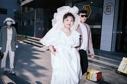 一位穿着白色连衣裙的女人戴着面具 和一位穿着婚纱的男人一起走在街上。