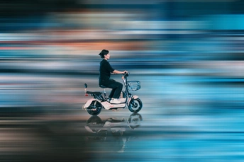 城市中一个模糊的男子骑滑板车的照片