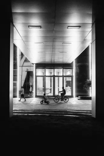 一个黑白建筑夜景照片 一个人骑自行车 一个人步行 一个人骑自行车。