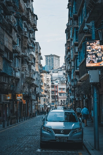 一条狭窄的城市街道 两边停满了车 人们沿着街道行驶。