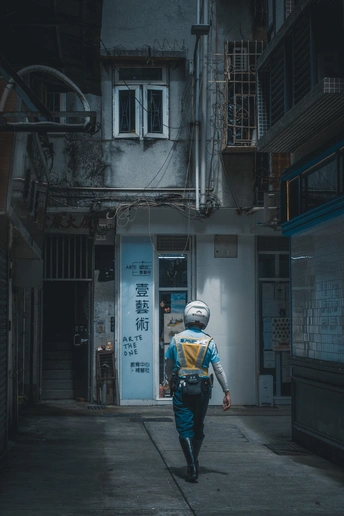 一个人晚上背着书包走在一个黑暗的巷子里