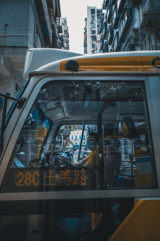 通过城市街道的出租车窗口看到建筑物背景和前景的公交车。