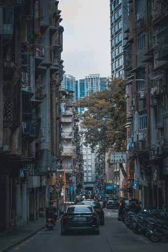 一条狭窄的城市街道 两侧停满了车辆 街道两侧都是高楼大厦。