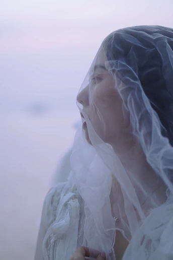 一个戴着面纱的女人望着雾蒙蒙的水面