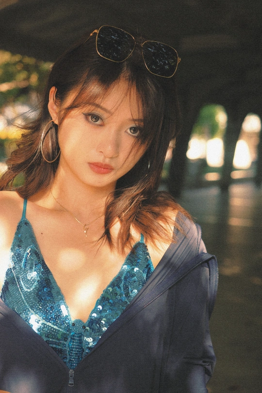 一个戴着墨镜和蓝色连衣裙的年轻女子站在伞下