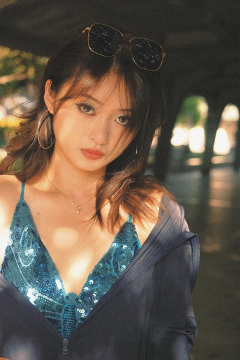 一个戴着墨镜和蓝色连衣裙的年轻女子站在伞下