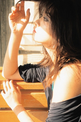 一位年轻女子坐在木长椅上 手戴眼镜望着窗外