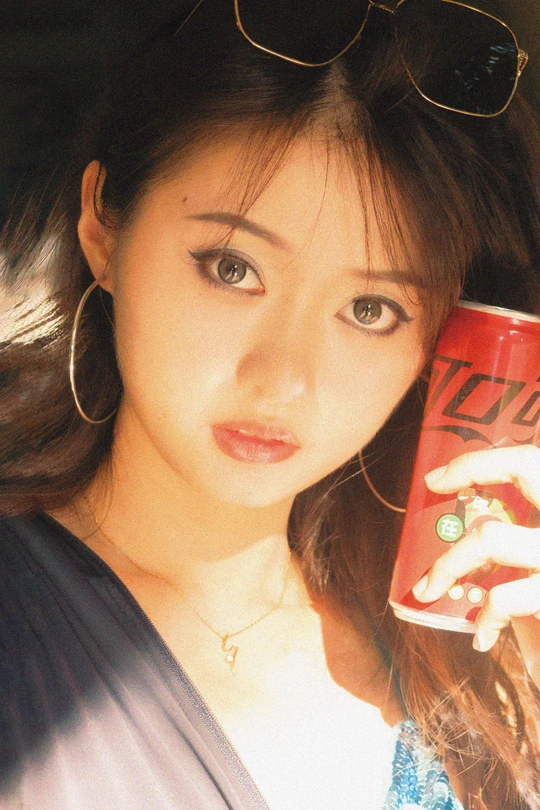 一个戴着墨镜的年轻女子拿着一个红色的咖啡杯 里面有饮料